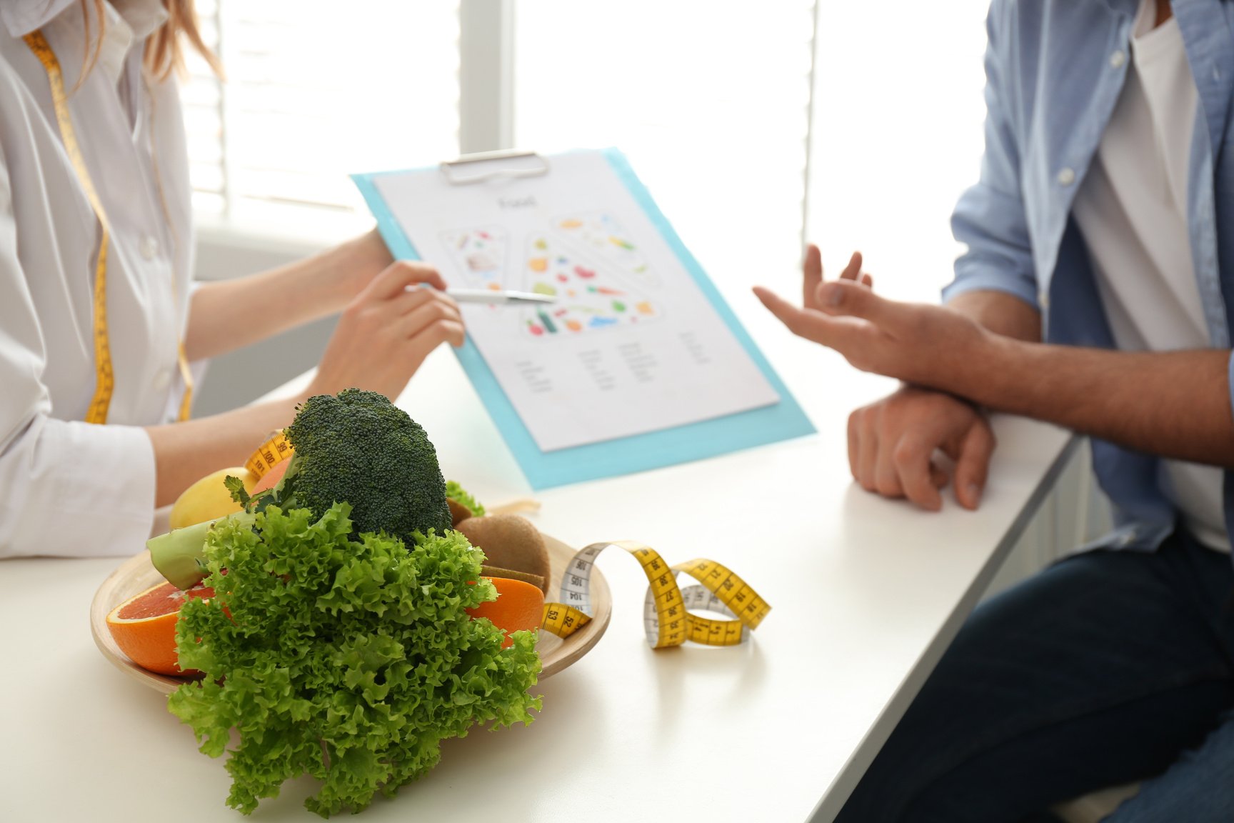 Young Nutritionist Consulting Patient at Table in Clinic, Closeu